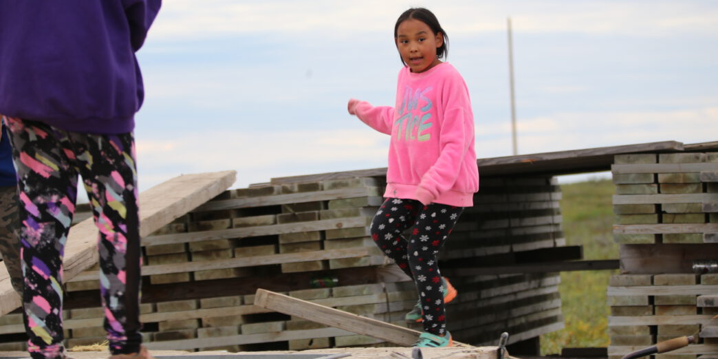 A summerday in the arctic: Two girls are playing on a pile of boards in the city of Nuiqsut.
