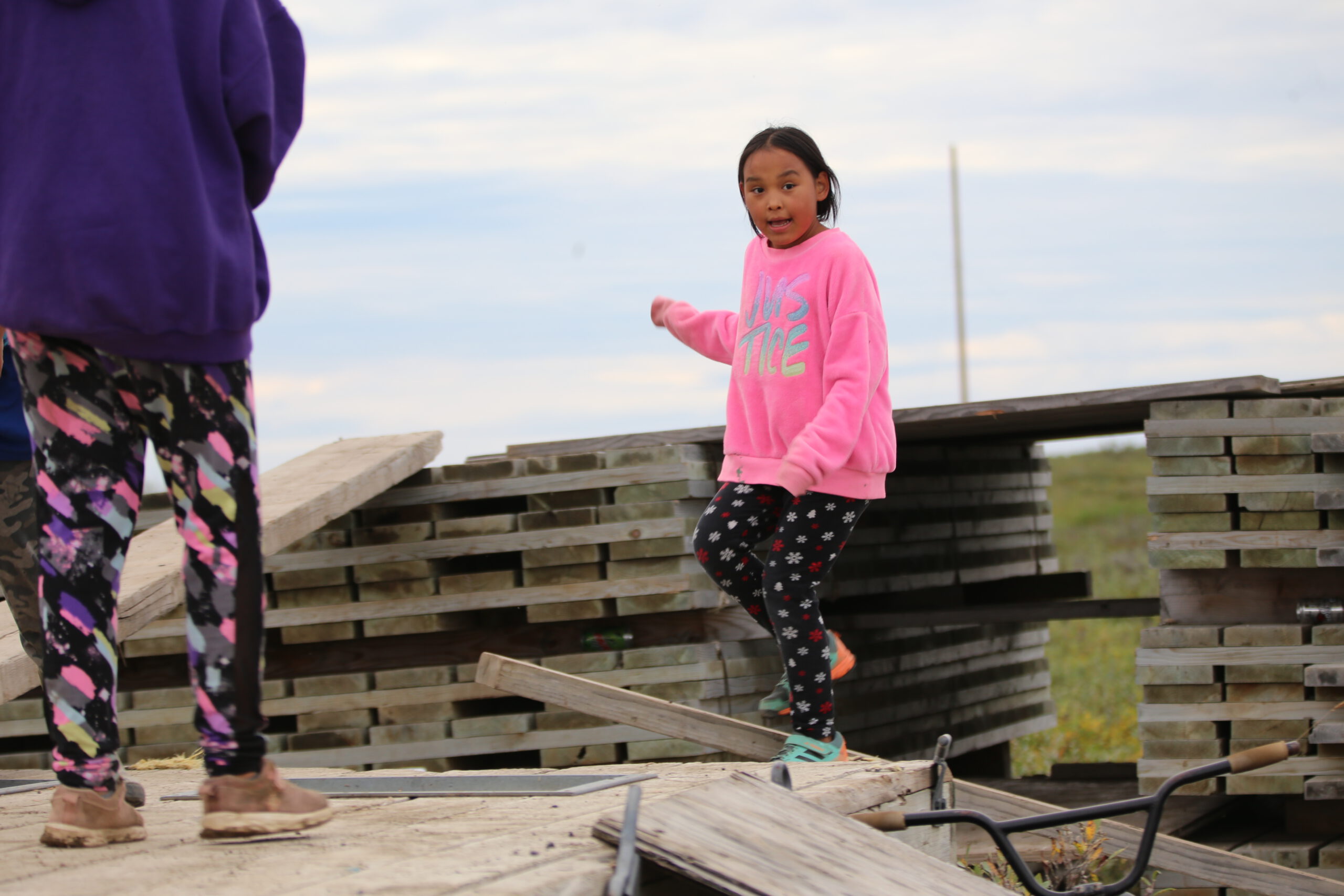 A summerday in the arctic: Two girls are playing on a pile of boards in the city of Nuiqsut.